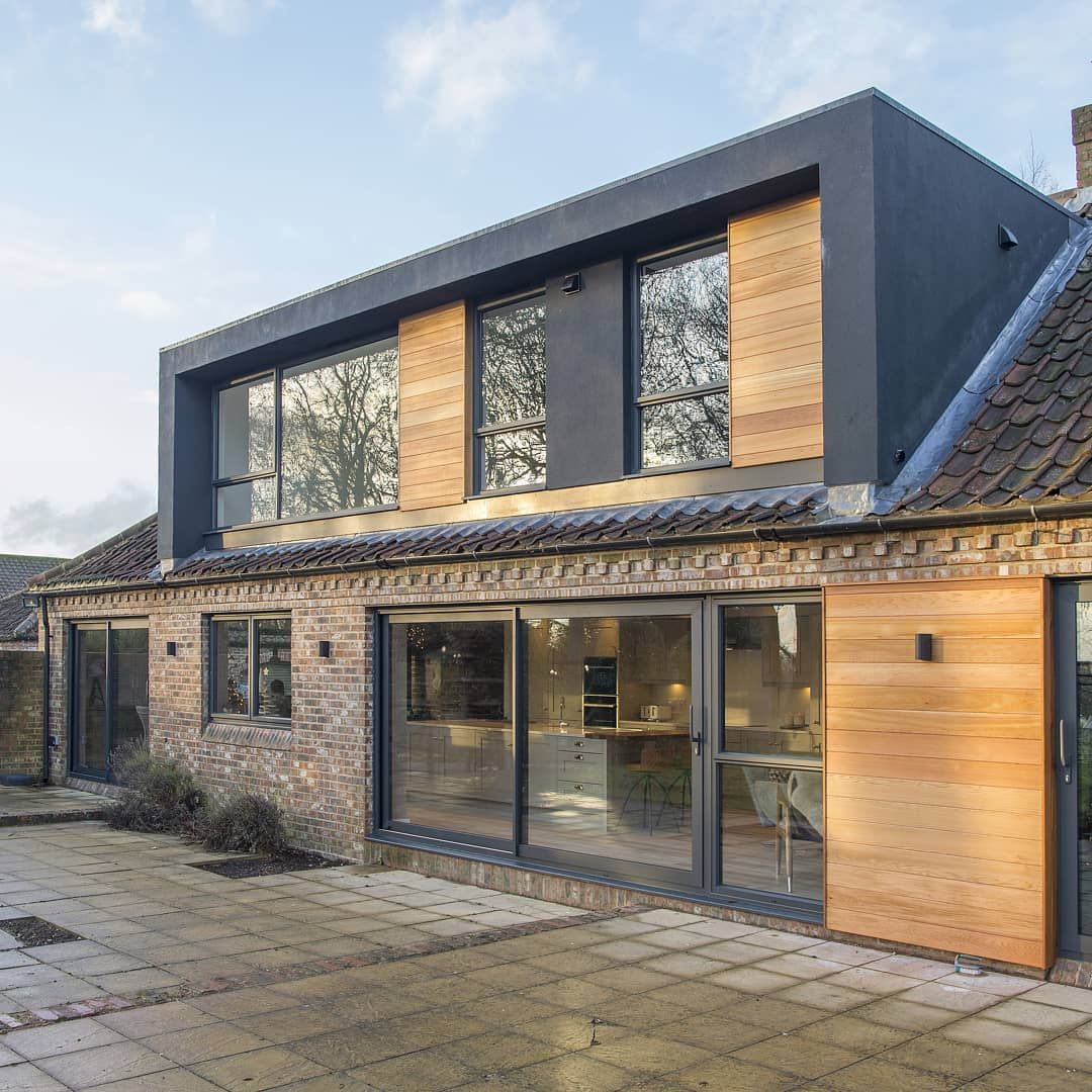 Grey sliding doors and windows on a brick and timber extension